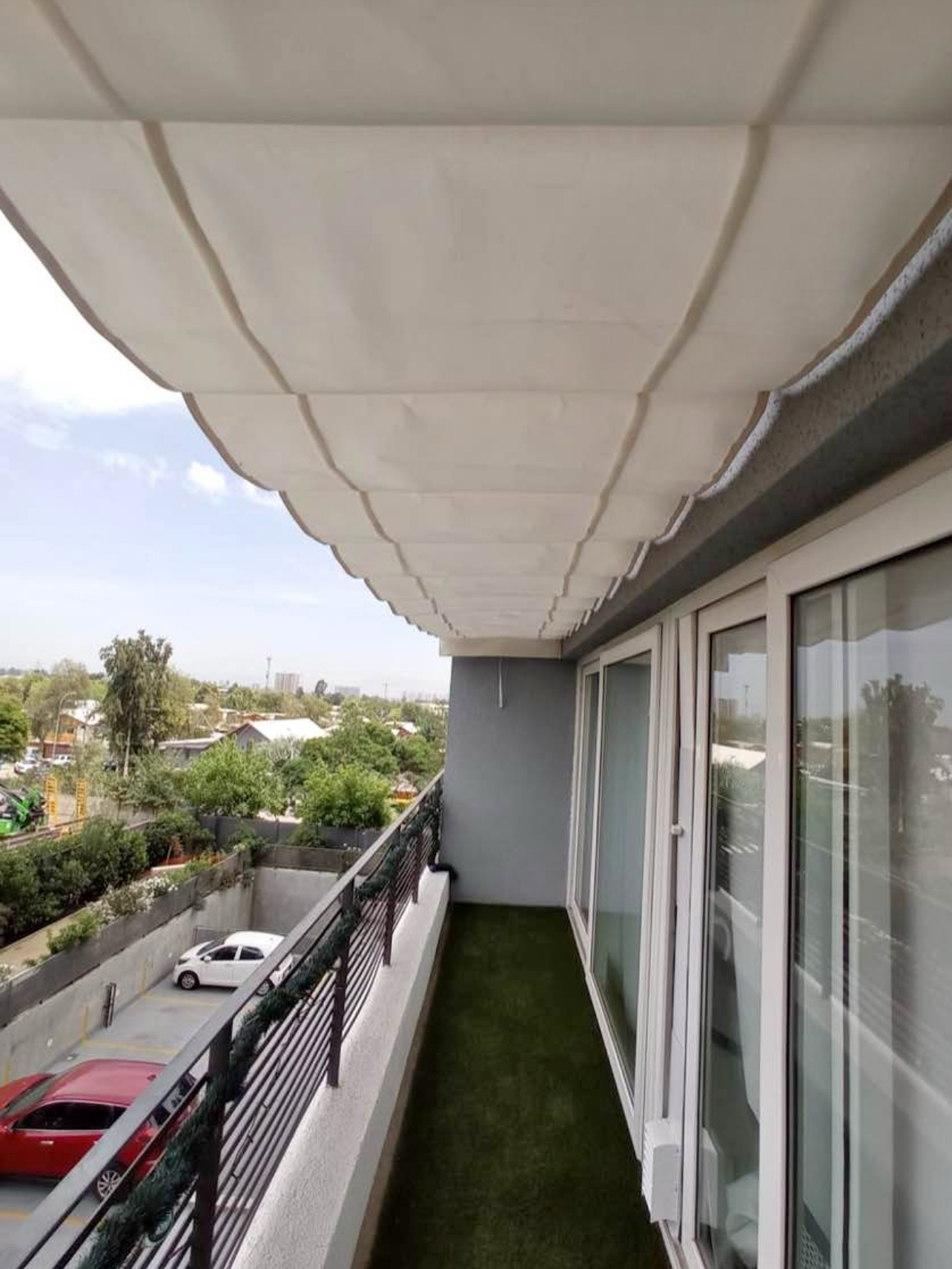 Terraza de departamento moderna con cierre de cristal plegable, amoblada con sofá. Terraza protegida del clima.