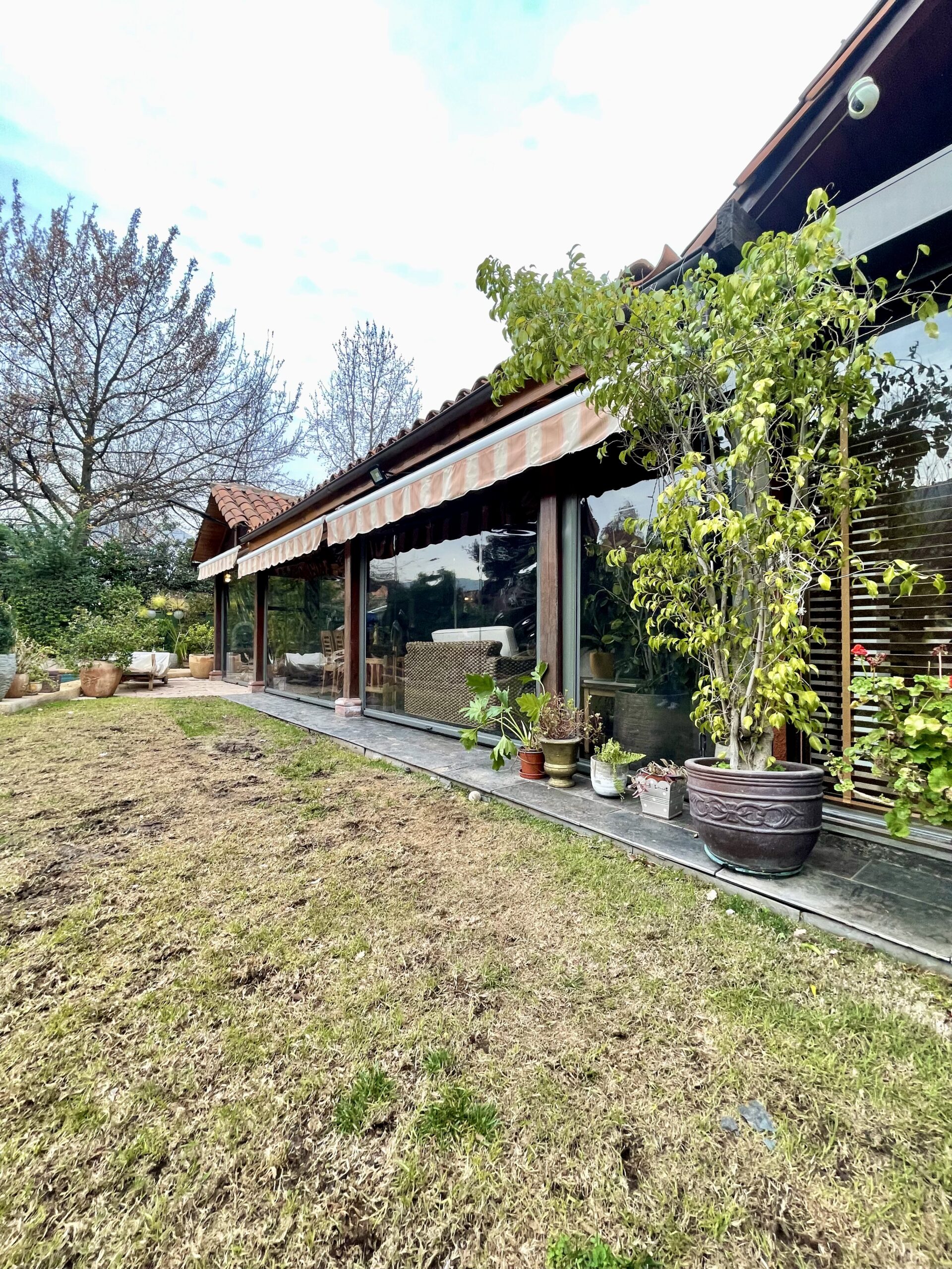 Terraza de departamento moderna con cierre de cristal plegable, amoblada con sofá. Terraza protegida del clima.