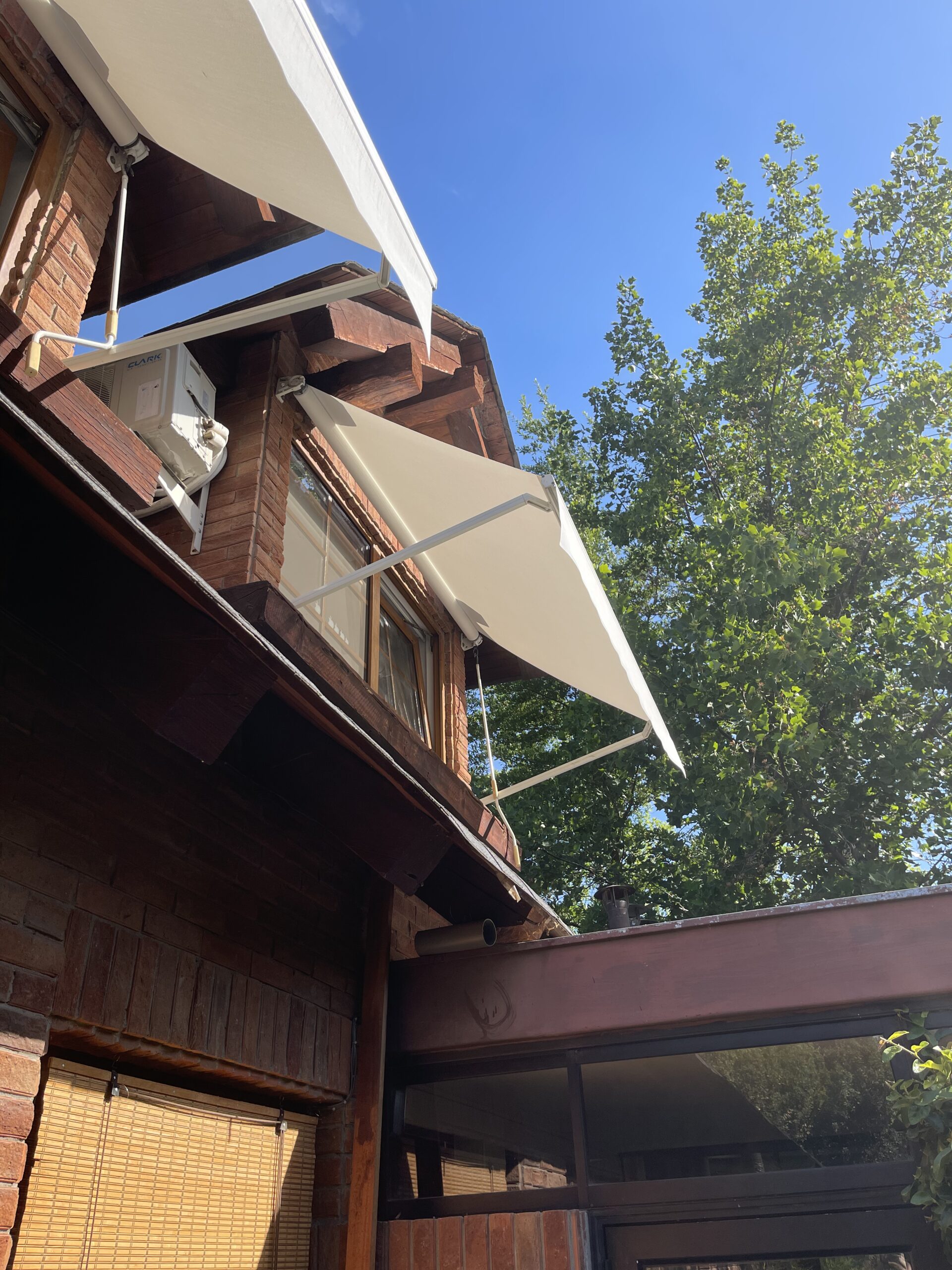 Terraza de departamento moderna con cierre de cristal plegable, amoblada con sofá. Terraza protegida del clima.