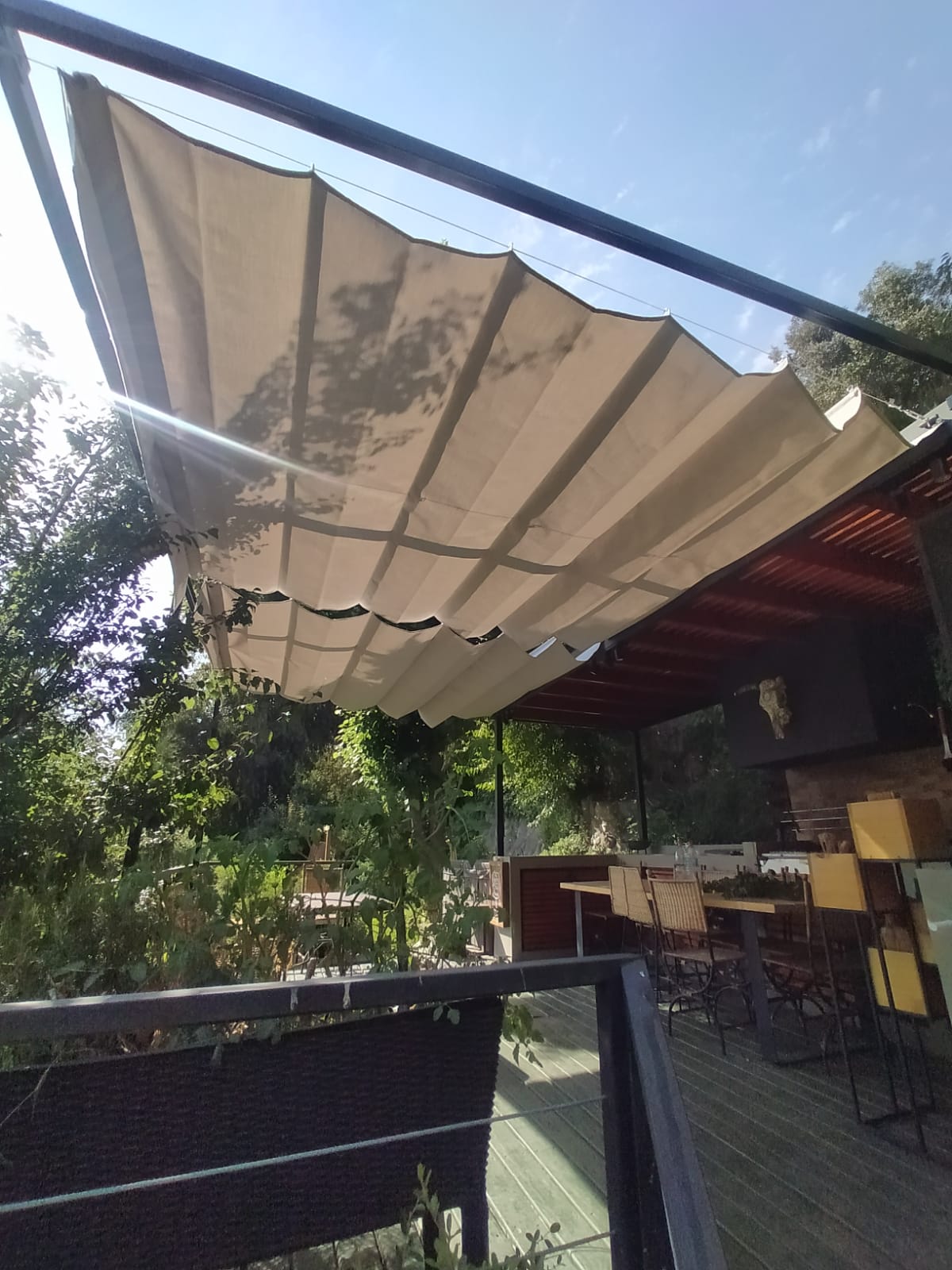 Terraza de departamento moderna con cierre de cristal plegable, amoblada con sofá. Terraza protegida del clima.